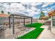 Backyard showcasing a modern pergola with a seating area, lush artificial turf, and desert landscaping at 6508 Peppermill Dr, Las Vegas, NV 89146