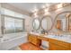 Bathroom featuring a large tub, double sinks with mirrors, and vanity lighting at 6508 Peppermill Dr, Las Vegas, NV 89146