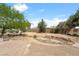 Desert landscaped backyard features a brick patio and a rock riverbed with mature trees at 6841 Longmeadow Dr, Pahrump, NV 89061