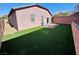 Private backyard featuring artificial turf, a covered patio, and a block wall for enhanced privacy at 7035 Thistle Ridge St, Las Vegas, NV 89166