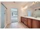 Bright bathroom with a double sink vanity, tiled floors, glass enclosed shower, and an open doorway at 7465 Widewing Dr, North Las Vegas, NV 89084