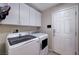 Laundry room includes full-size washer and dryer, upper cabinets for storage, and exterior door at 7606 Grove Acre Ct, Las Vegas, NV 89131