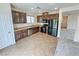Well-lit kitchen with brown cabinets, stainless steel dishwasher, and black appliances with tile flooring at 7815 Shingle Beach St, Las Vegas, NV 89166