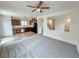 Open-concept living area with grey carpet, ceiling fan, and view of the kitchen with wood cabinets at 7815 Shingle Beach St, Las Vegas, NV 89166