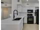 White kitchen featuring quartz countertop, black hardware and appliances, and tiled floors at 9050 W Warm Springs Rd # 1117, Las Vegas, NV 89148