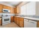 Well-lit kitchen featuring tile flooring, wood cabinetry, and white appliances including gas range and dishwasher at 940 Rifle Dr, Henderson, NV 89002