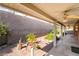 Covered patio with ceiling fans overlooks landscaped backyard with block wall for added privacy at 940 Rifle Dr, Henderson, NV 89002