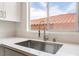 Close-up of a modern kitchen sink with a bright window view and white countertops at 10505 Jeremy Ridge Ave, Las Vegas, NV 89144