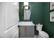 Stylish powder room featuring a modern vanity, unique mirror, and accent lighting on a bold green wall at 10781 Agate Cliffs Ave, Las Vegas, NV 89135