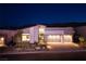 Stunning home exterior featuring a three-car garage, modern architecture, and lush landscaping at dusk at 10781 Agate Cliffs Ave, Las Vegas, NV 89135
