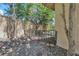 Close up of backyard with wrought iron gate, mature tree, decorative rock and brick border, and tan block wall at 1813 Skyline Dr, Las Vegas, NV 89117