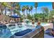 Backyard view of hot tub next to sparkling swimming pool with lush landscaping and palm trees at 1813 Skyline Dr, Las Vegas, NV 89117