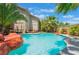 Lush tropical landscaping surrounds the blue backyard pool, with rock features, palm trees, and serene setting at 2008 Aspen Oak St, Las Vegas, NV 89134