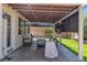 Comfortable covered patio with ample seating, lighting, mounted TV, and view of the green backyard at 217 Turkey Creek Way, Henderson, NV 89074