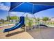 A playground with various climbing structures and a blue slide is covered by a blue awning for sun protection at 2773 Green Envy Ave # 245, North Las Vegas, NV 89086