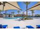 A community pool is surrounded by lounge chairs and sun shades, as well as lush palm trees and tropical landscaping at 2773 Green Envy Ave # 245, North Las Vegas, NV 89086