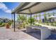 A covered outdoor sitting area has a concrete bench and table, complemented by small trees, shrubs, and flowers at 2773 Green Envy Ave # 245, North Las Vegas, NV 89086