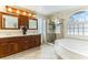 Bright bathroom boasts dual vanities, glass enclosed shower and a garden tub beneath a large arched window at 2829 Via Florentine St, Henderson, NV 89074