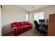 Comfortable bedroom with carpet flooring, a large window, and a red couch at 2924 Sunday Silence Rd, North Las Vegas, NV 89086