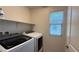Convenient laundry room with modern appliances, shelving, and a bright window at 2924 Sunday Silence Rd, North Las Vegas, NV 89086