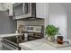 Close up shows stainless steel oven and microwave alongside modern white countertops and a mosaic backsplash at 5171 Lindell Rd # 201, Las Vegas, NV 89118