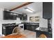 Bright kitchen with black cabinets, marble countertops, wooden beam, and modern appliances at 5230 Whispering Robin Ln, Mount Charleston, NV 89124