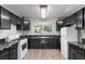 Well-lit kitchen featuring black cabinets, marble countertops, and modern white appliances at 5230 Whispering Robin Ln, Mount Charleston, NV 89124