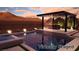 Backyard pool at dusk with modern waterfall, bar seating, and outdoor lighting perfect for relaxation at 5364 Succulent Rose Dr, Las Vegas, NV 89135