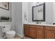 Bathroom features a toilet and single sink vanity with a framed mirror and wood cabinets at 7001 Via Locanda Ave, Las Vegas, NV 89131