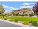 Beautiful home exterior with lush green lawn, landscaped with bushes and flowers at 7001 Via Locanda Ave, Las Vegas, NV 89131