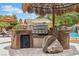 Outdoor kitchen area featuring a built-in grill, bar seating, and tropical landscaping at 7001 Via Locanda Ave, Las Vegas, NV 89131