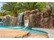Resort-style pool featuring a rock waterfall and slide surrounded by lush landscaping at 7001 Via Locanda Ave, Las Vegas, NV 89131