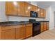 Well-lit kitchen featuring wooden cabinetry, black appliances, and granite countertops at 705 Coastal Lagoon St, Henderson, NV 89002