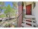 Welcoming condo entrance via stairs, featuring neutral tones, a red door, and a view of mature landscaping at 950 Seven Hills Dr # 1921, Henderson, NV 89052