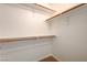 Bright walk-in closet features wood rods, white shelving and brackets, and neutral carpet at 950 Seven Hills Dr # 1921, Henderson, NV 89052