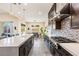 A well-lit kitchen featuring a long white countertop island, dark cabinetry, and stainless steel appliances at 11672 Barga Ct, Las Vegas, NV 89138