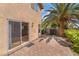 Charming backyard patio featuring brick pavers, sliding glass door to the home's interior, and a mature palm tree at 1220 Padre Serra Ln, Las Vegas, NV 89134