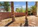 Spacious backyard with a partial view of the house, brick wall fencing, and mature trees at 1220 Padre Serra Ln, Las Vegas, NV 89134