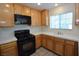 Well-lit kitchen with wooden cabinets, black appliances, and a corner sink under a window at 1220 Padre Serra Ln, Las Vegas, NV 89134