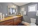 Gray bathroom with a stone countertop, brown cabinets, a window, and framed mirror at 15 Pheasant Ridge Dr, Henderson, NV 89014