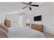 Bright bedroom featuring a ceiling fan, wall-mounted TV and view to an ensuite bathroom with soaking tub at 15 Pheasant Ridge Dr, Henderson, NV 89014