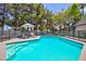 Sparkling pool with lounge chairs, umbrella, and lush landscaping for outdoor relaxation at 15 Pheasant Ridge Dr, Henderson, NV 89014