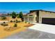 Exterior elevation of tan-colored home with desert landscaping and a two-car garage at 1801 S Manzanita Dr, Pahrump, NV 89048