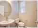 A half bathroom features a pedestal sink, toilet, round mirror, and a window with blinds at 2369 Via Barranca St, Henderson, NV 89044