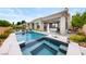 Backyard with a pool, jacuzzi, lush landscaping, outdoor seating, and a covered patio, perfect for outdoor entertaining at 2820 High Range Dr, Las Vegas, NV 89134