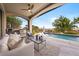 Inviting covered patio with a pizza oven, grill, outdoor seating, and a view of the pool and beautifully landscaped yard at 2820 High Range Dr, Las Vegas, NV 89134