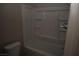 Well-lit bathroom boasts updated bathtub with shelving, a toilet, and new finishes at 3101 E Carey Ave, North Las Vegas, NV 89030