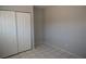 This bedroom features tile floors, neutral gray paint, and closet with white bi-fold doors at 3101 E Carey Ave, North Las Vegas, NV 89030