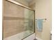 Bathtub shower combo with glass door and beige tile surround and silver hardware at 3159 Via Como, Henderson, NV 89044