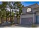 Two-story home featuring a grey garage door and lush trees on an adequately sized lot at 3481 Creek River Dr, Las Vegas, NV 89129